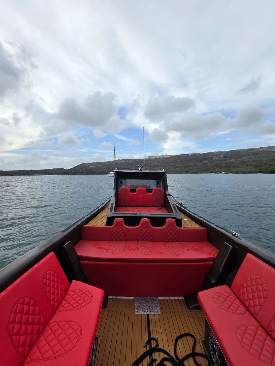 Red upholstered seating and wood-look deck viewed from the bow