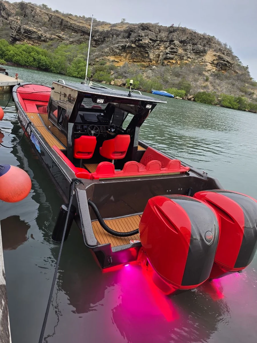 Stern view of the red-and-black boat, with twin red outboard motors and open seating