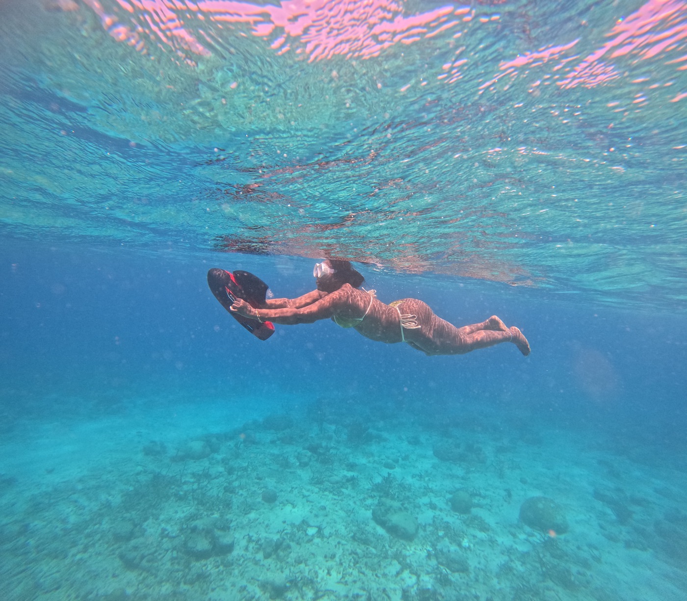 Swimmer holding an underwater scooter above the seabed